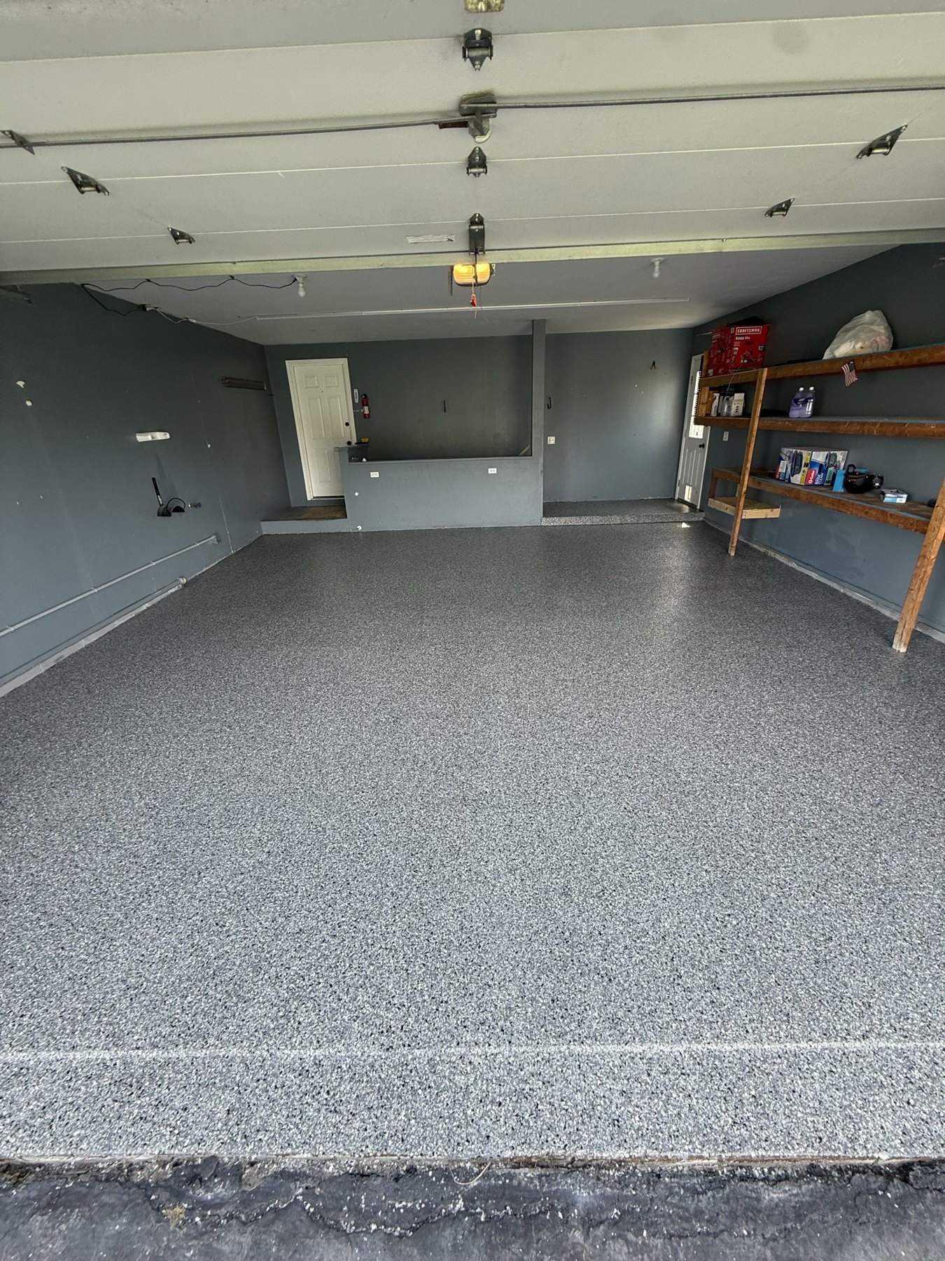 Gray flake epoxy garage floor with workshop shelving along the wall